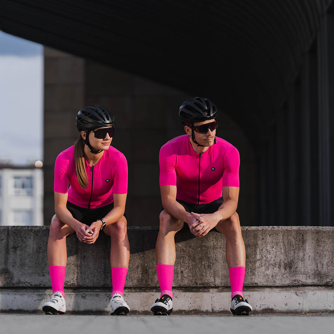 female and male cyclists wearing pink cycling kit with matching colors